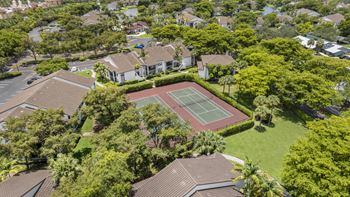 A tennis court is surrounded by apartments and trees.